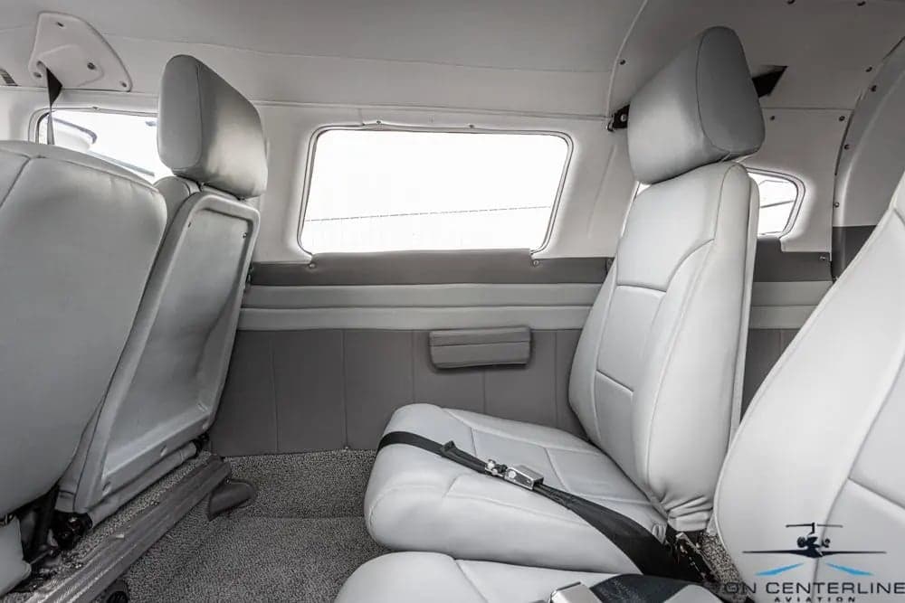 View of the cabin of a Piper PA-32R-301 Saratoga SP, featuring gray leather seats and a window.
