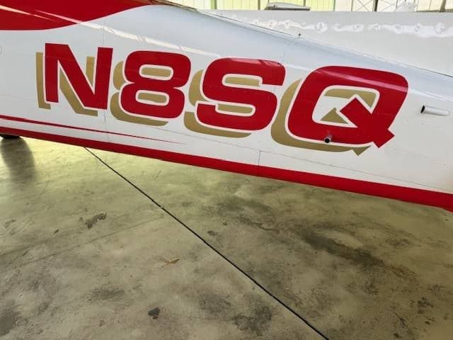 A close-up of the red and gold tail number N8SQ on the white fuselage of the aircraft.