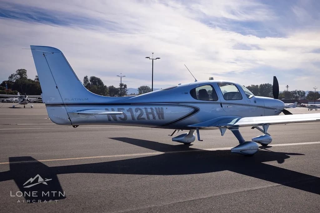 Rear-right side view of a silver Cirrus SR22 aircraft, N512HW, parked on an airfield.