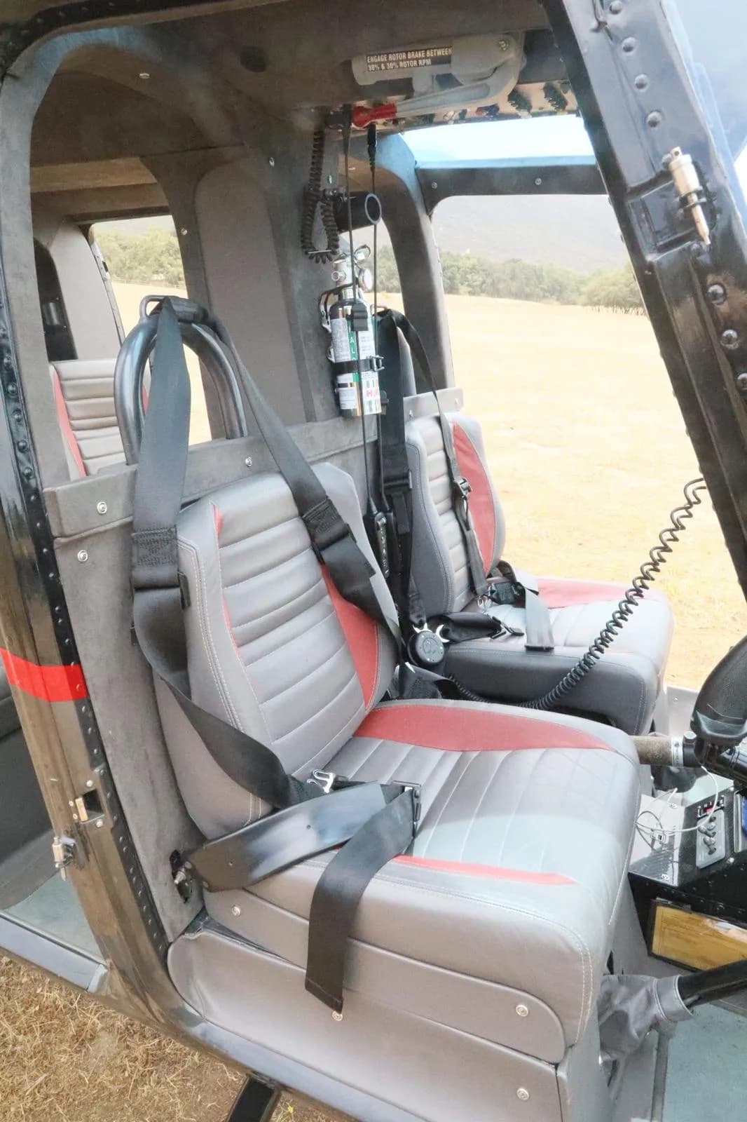 The gray and red upholstered interior seats of a Bell 206 JetRanger helicopter cabin.