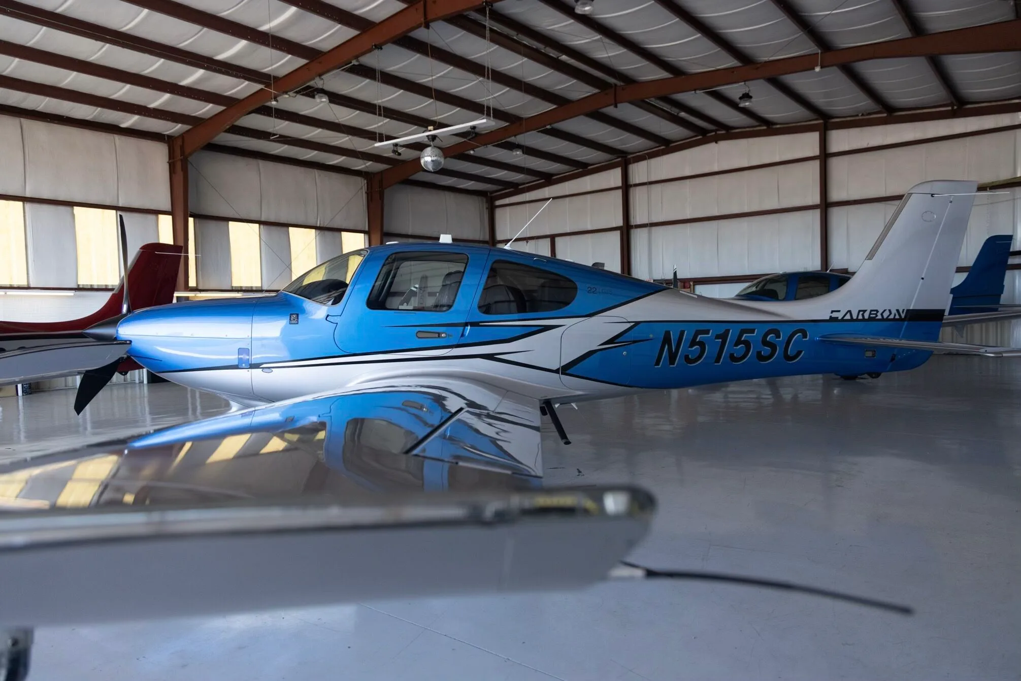 A blue and silver Cirrus SR22 aircraft (N515SC) parked inside a hangar.