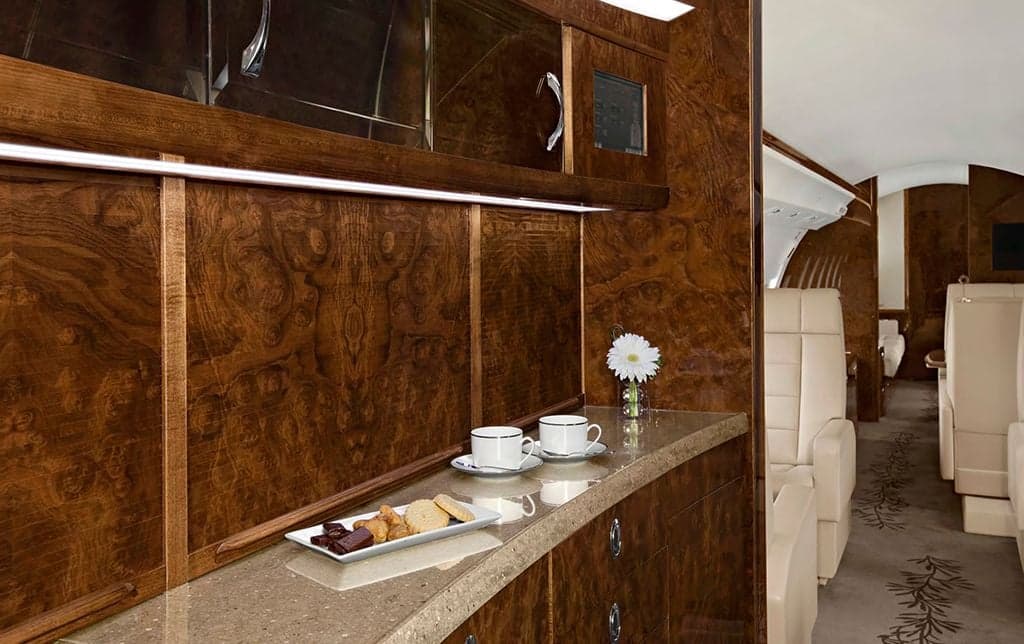 A galley area inside the aircraft with wood cabinetry and refreshments.