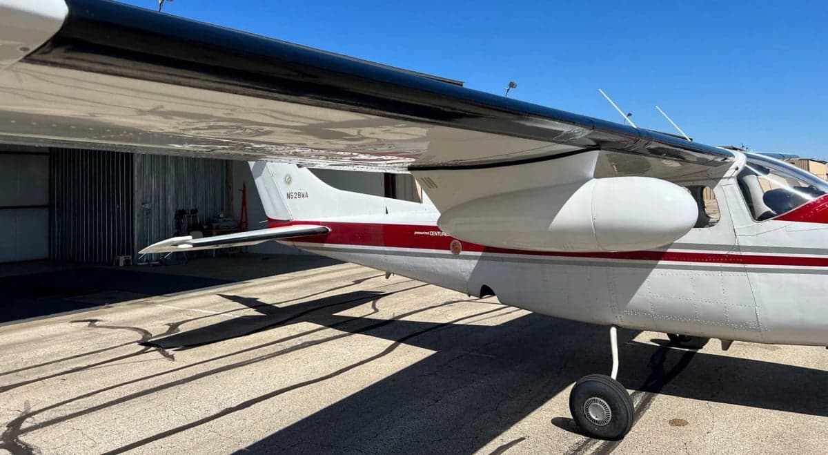Side view of the right wing and fuselage of a red and white aircraft, registration N528WA, showing the landing gear.