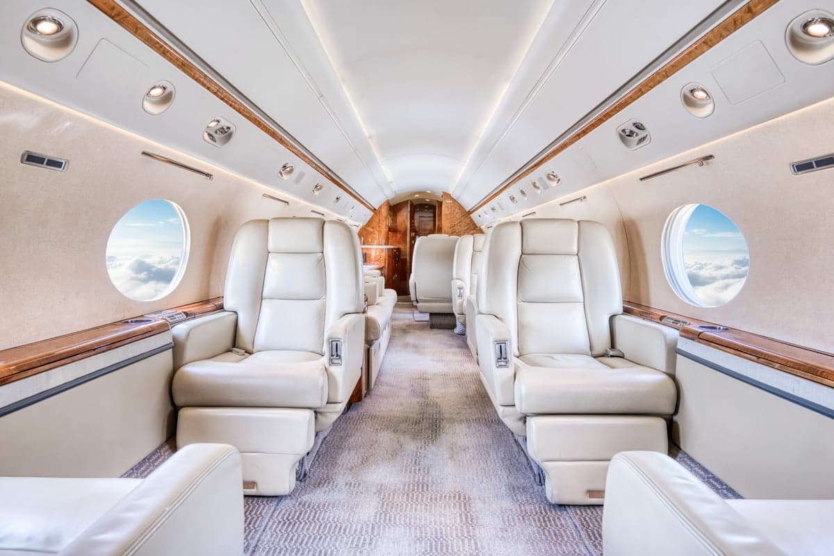 A view of the aircraft's interior cabin with leather seats and wood trim.