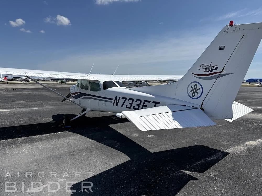 A rear quarter view of the white Cessna Skyhawk N733FT showing its tail and right wing on an asphalt ramp.