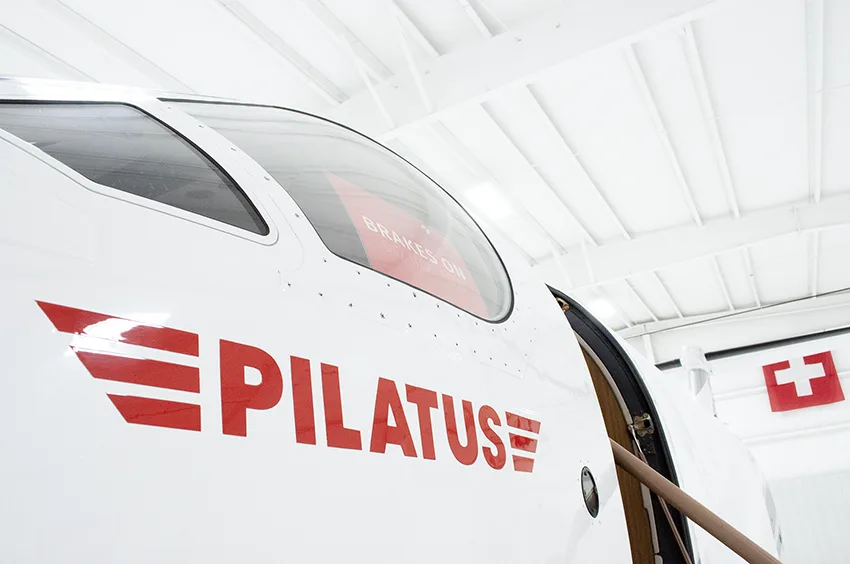 A detailed close-up of the white main landing gear strut and wheel of the Pilatus PC-12NG aircraft.