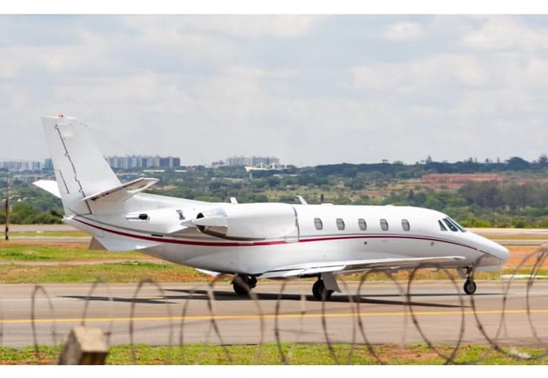 A white Cessna Citation XLS aircraft is on the tarmac with a red stripe.