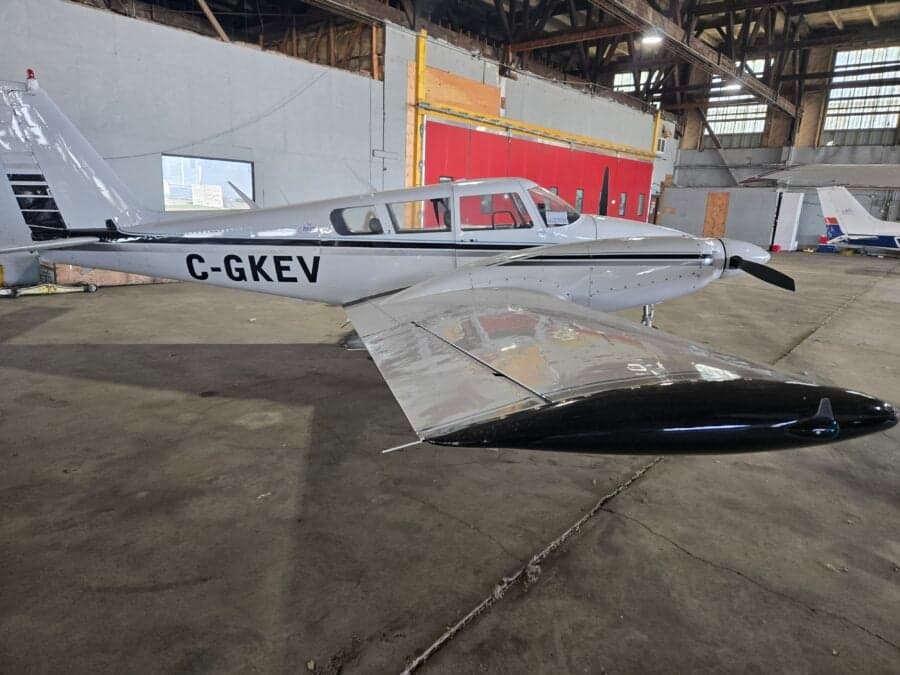 A white and black Piper PA-39 Twin Comanche is parked in a hangar.