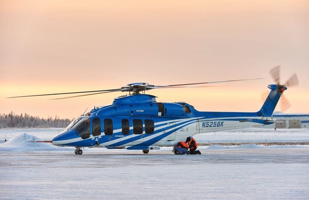 A blue and white Bell 525 helicopter parked on a snowy airfield.