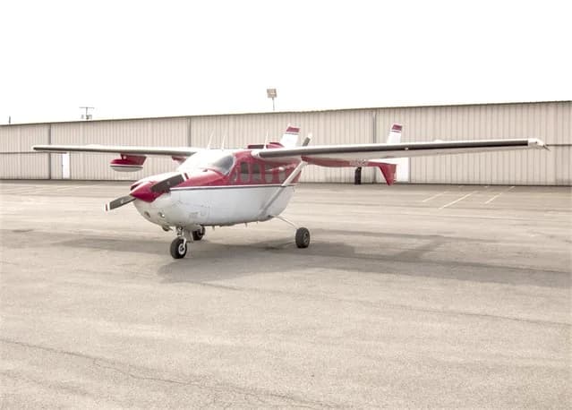 Side view of a red and white Cessna Skymaster on the tarmac.