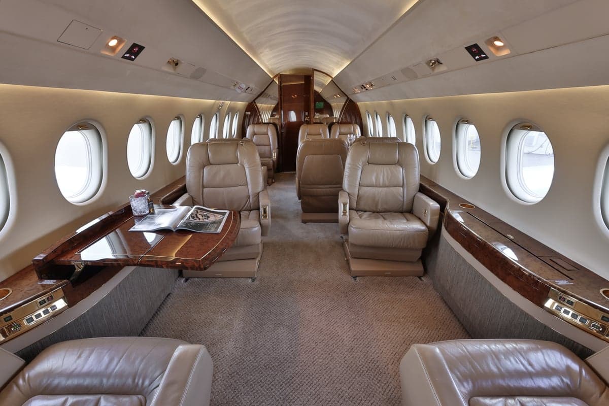 View of the aircraft interior with leather seats and wood tables.