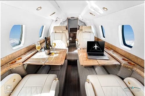 A view of the aircraft's interior, featuring leather seats and wooden tables.