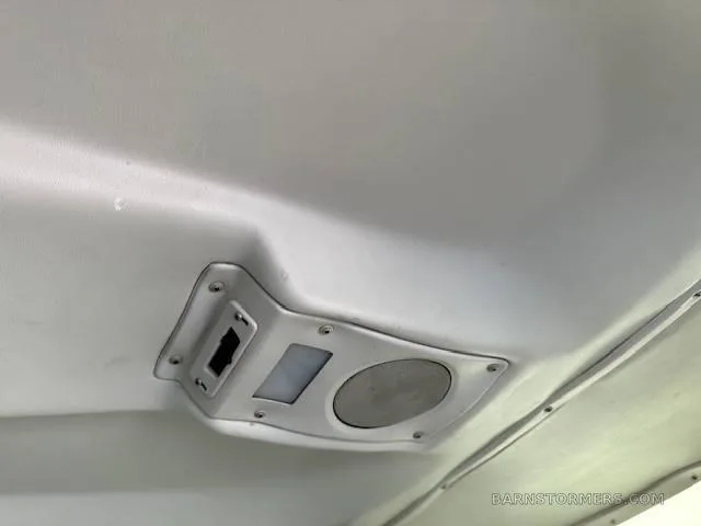 A white overhead panel with a light and speaker is mounted on the aircraft's ceiling.