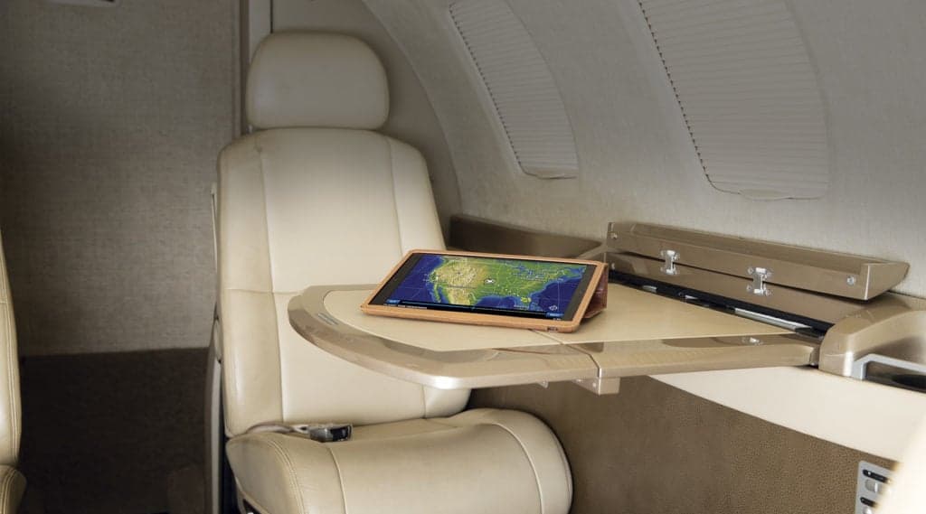 The interior of a Citation M2 aircraft with a table and tablet showing a map.