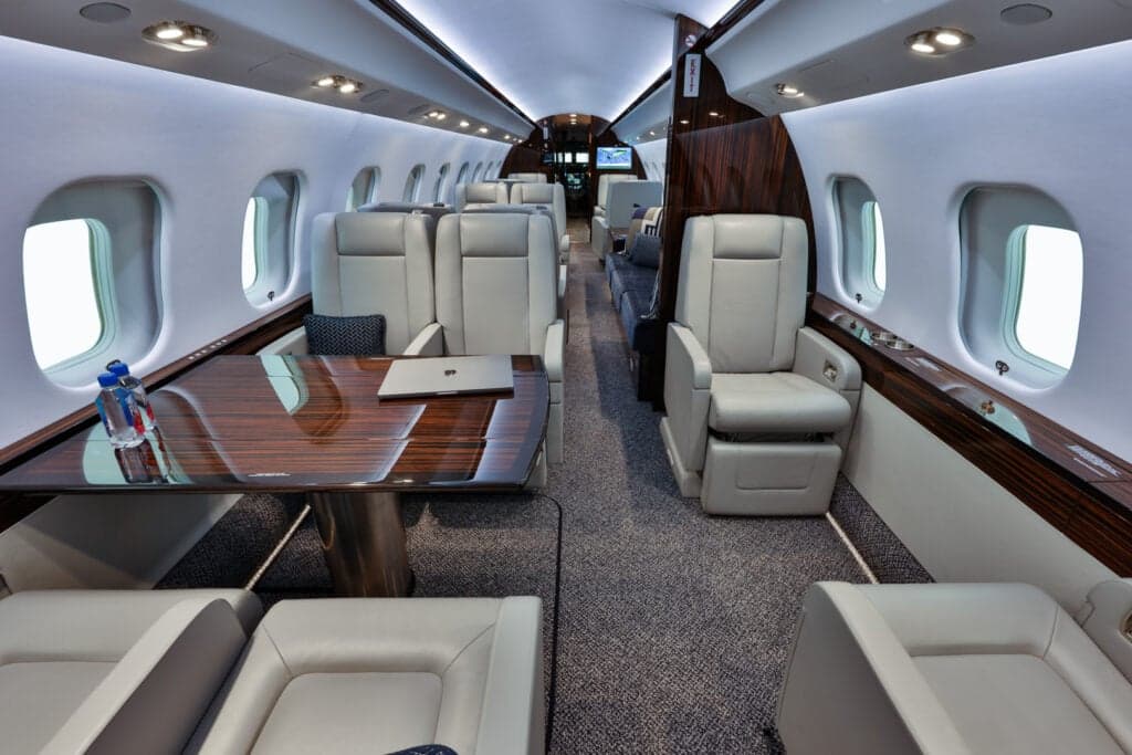 View of the aircraft interior showing the seating arrangement and a table with a laptop.