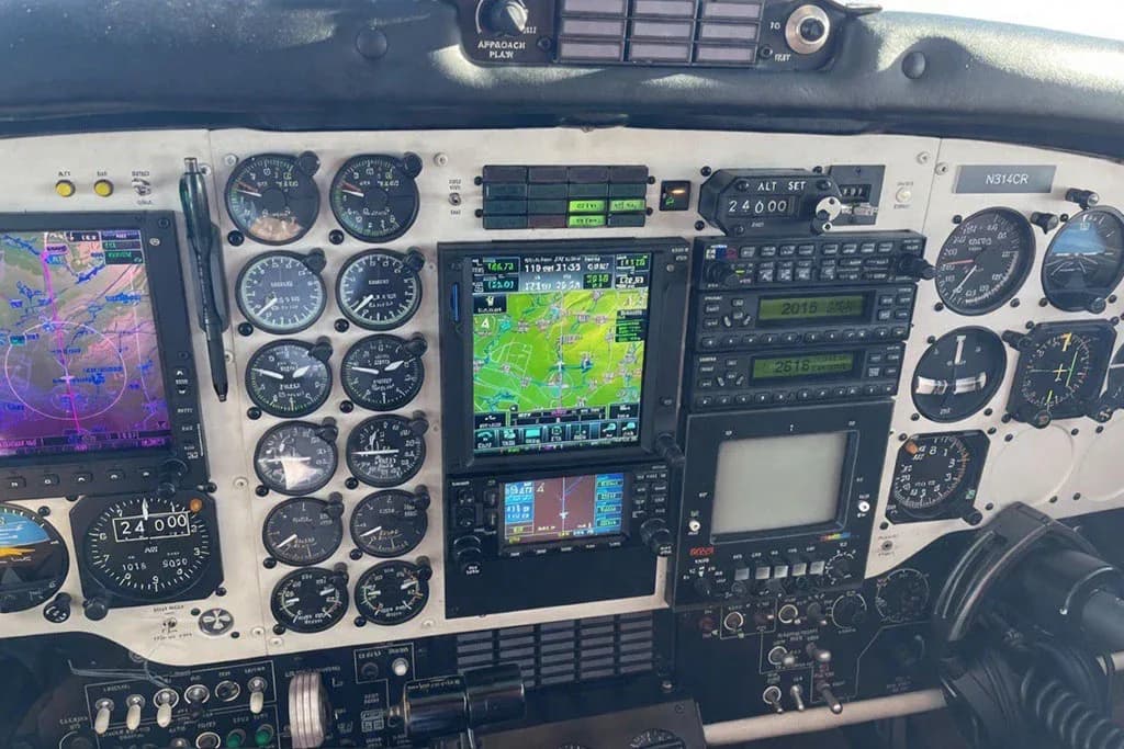 The detailed instrument panel of a Beechcraft King Air cockpit, featuring multiple analog gauges and modern digital displays.