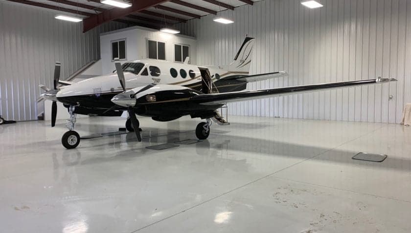 Full side view of the aircraft in a hangar, showing the wings and open door.