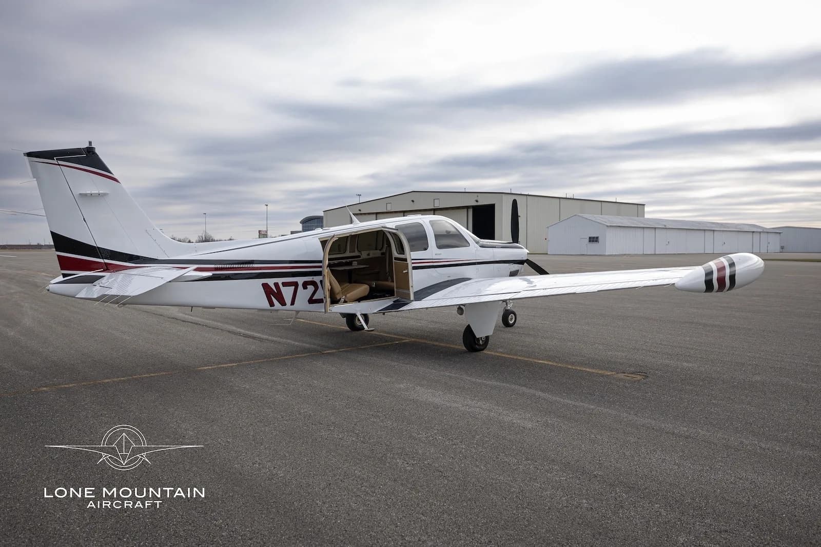 The N721EN single-engine propeller aircraft parked on an airfield with its passenger door open, revealing the interior.