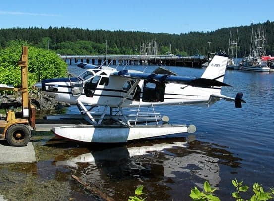 A de Havilland Beaver floatplane is docked at a pier.