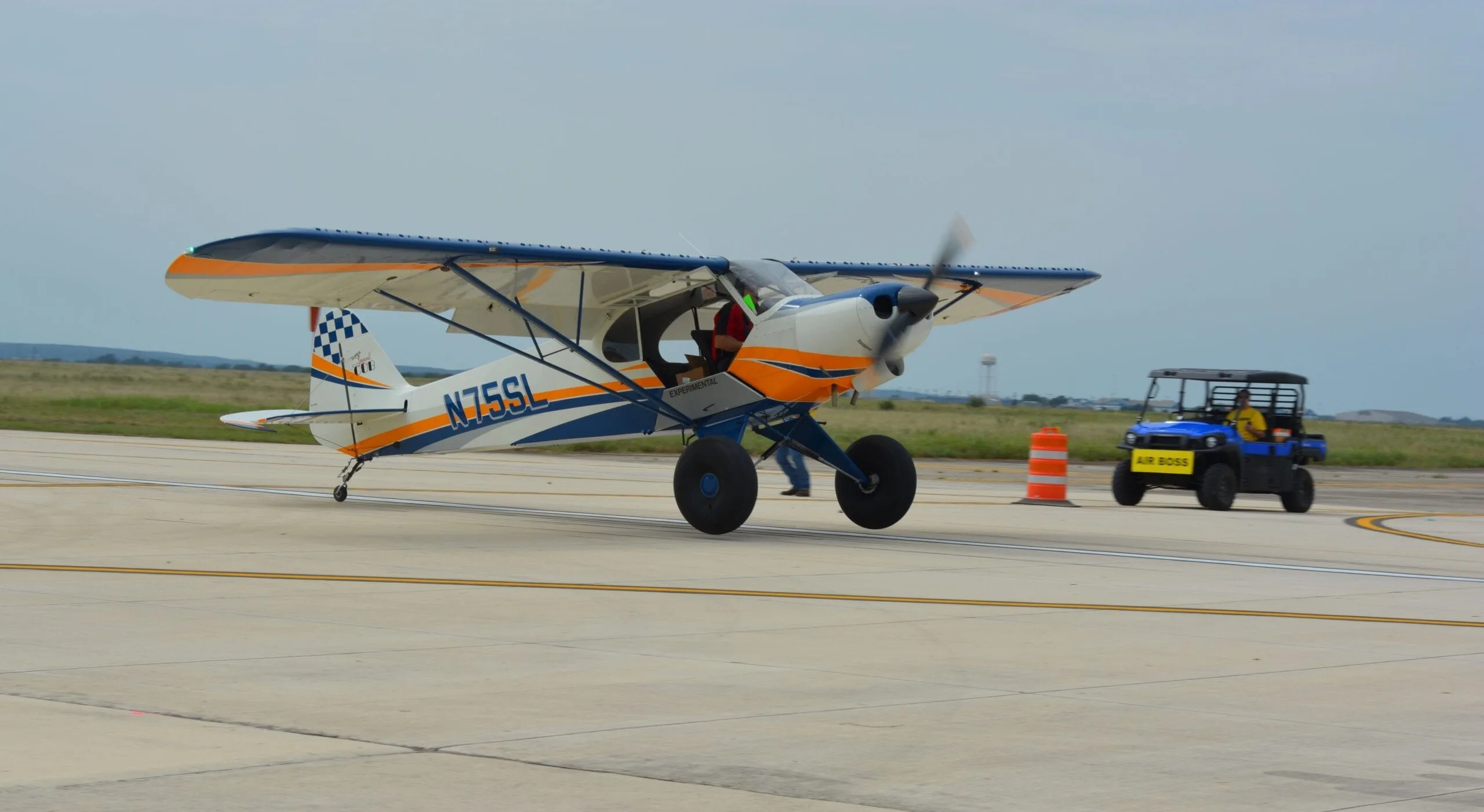 Side view of a white, blue, and orange aircraft on the ground.