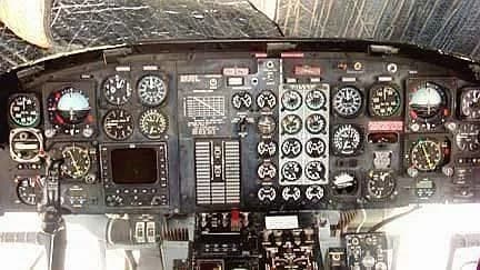 A detailed view of a helicopter cockpit instrument panel with numerous gauges and controls.