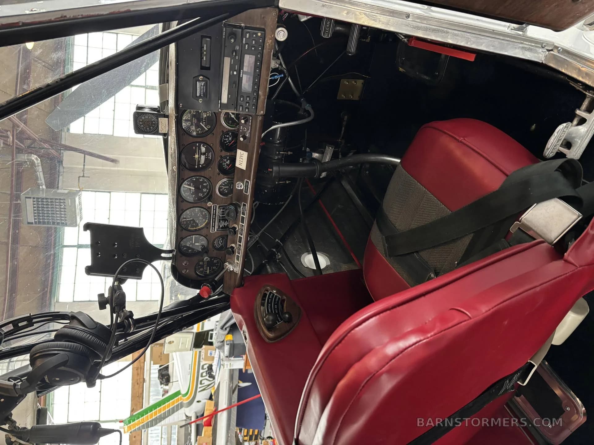 The cockpit of a light aircraft, showing the instrument panel with gauges and red upholstered seats.