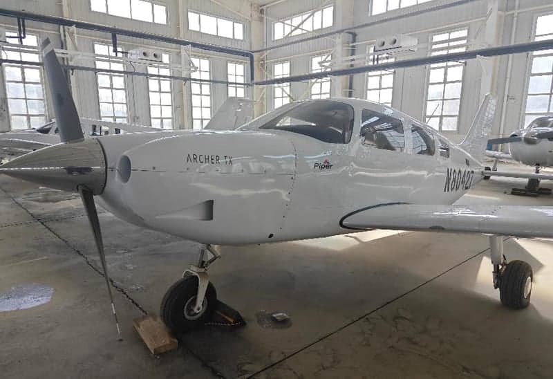 Front view of a Piper Archer TX aircraft, registration N80427, inside a hangar.