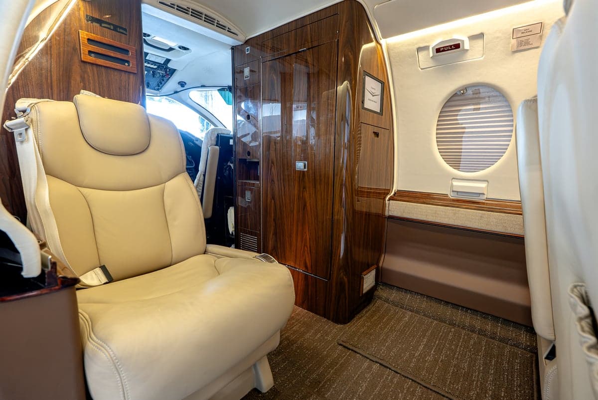 View of the Learjet interior showing a tan leather seat and wood accents.
