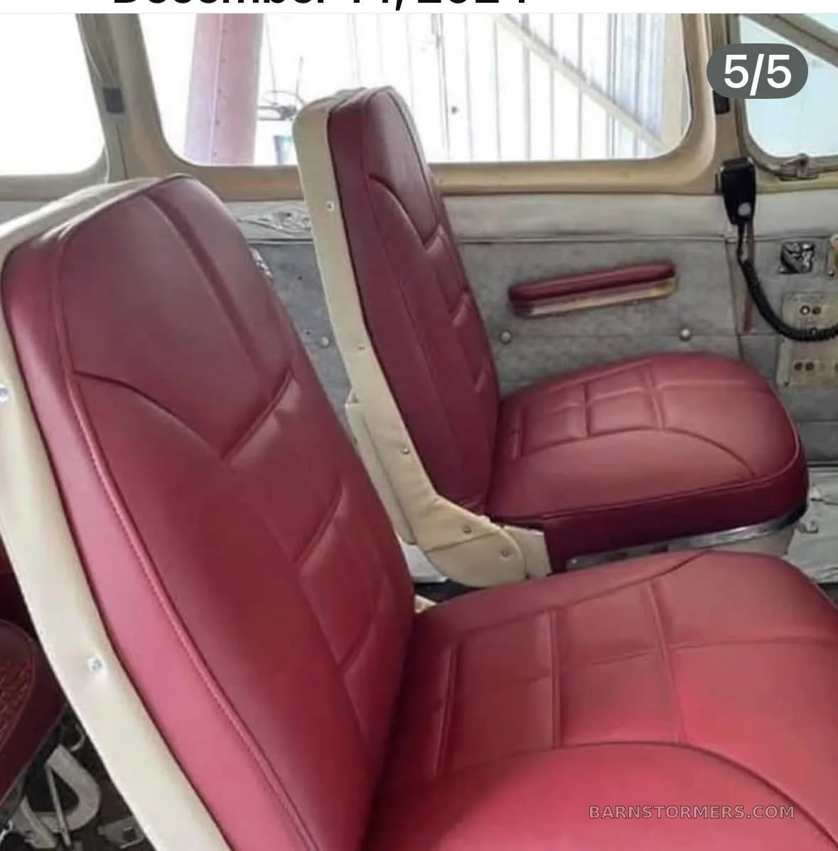 Two red upholstered passenger seats inside an aircraft cabin.