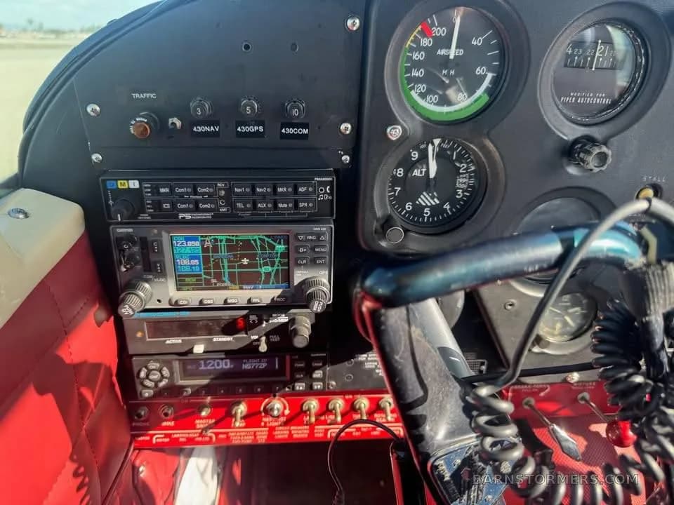 A close-up view of an aircraft cockpit with various analog gauges, a GPS display, and radio equipment.