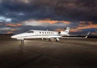 A Learjet 45XR aircraft is parked on the tarmac at dusk.