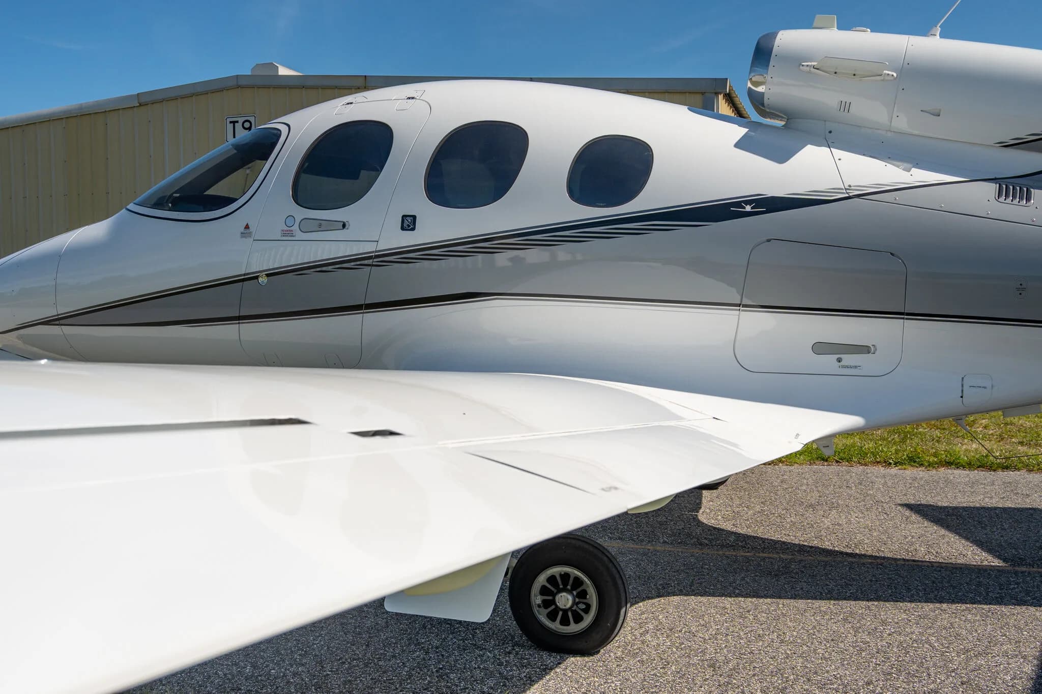 Close-up of the white and grey fuselage and wing of the Cirrus Vision Jet N73SG.