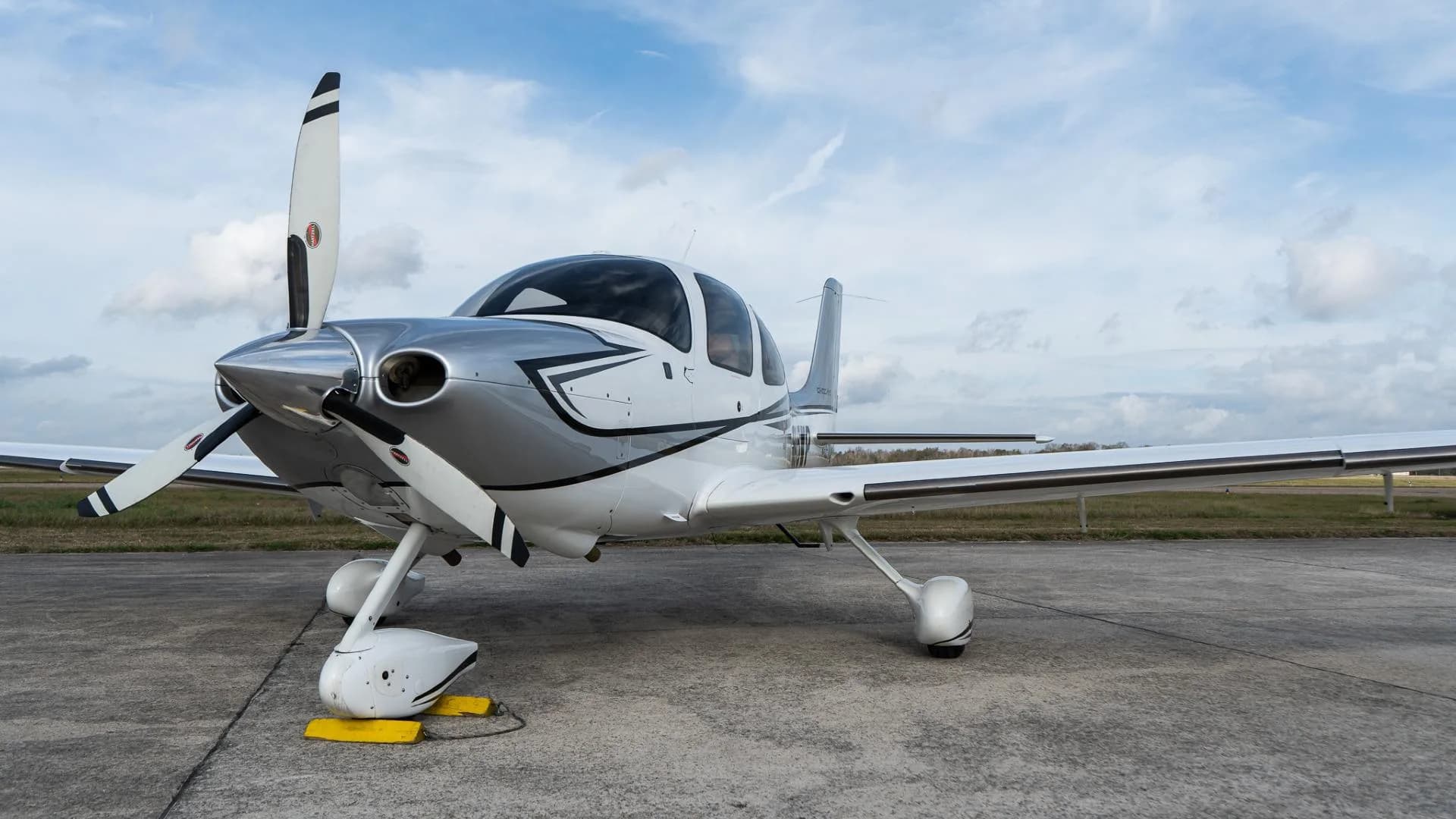 Low angle front view of a white Cirrus SR22 aircraft with a three-bladed propeller.