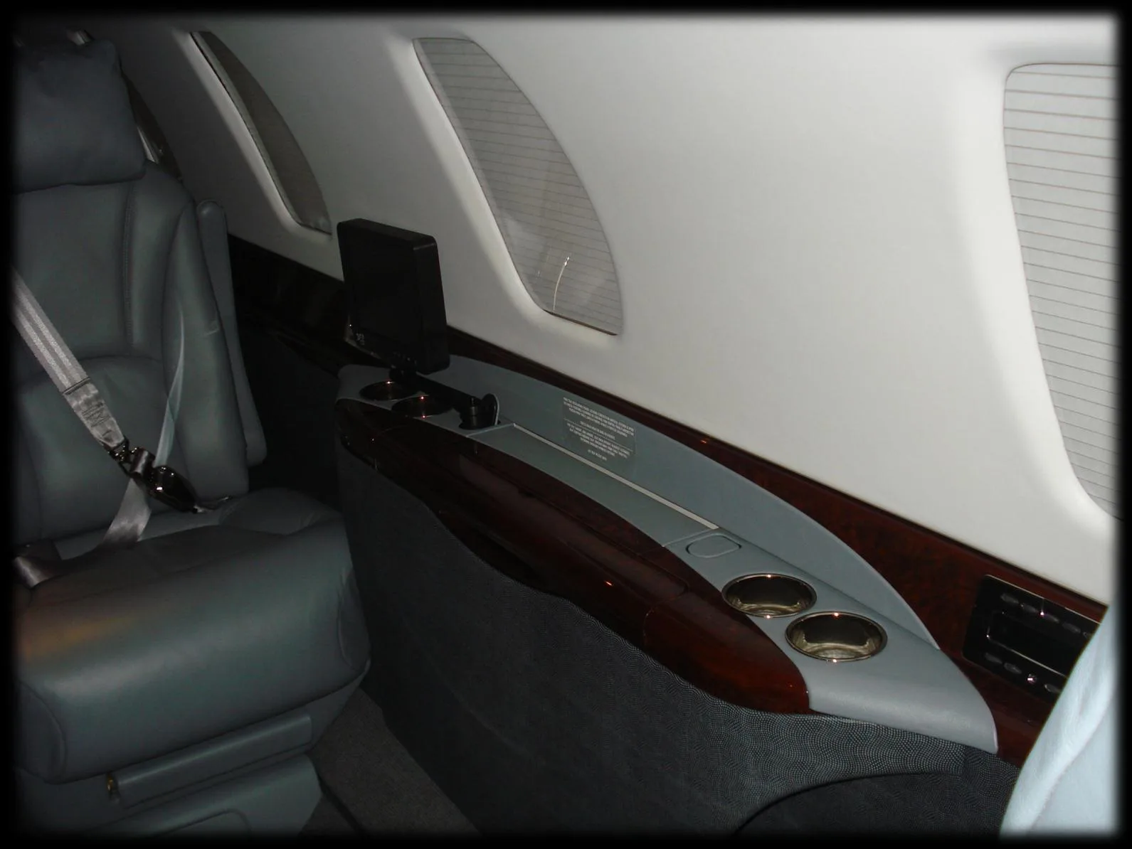 Close up of the cabin seat and side console with cup holders and a monitor.