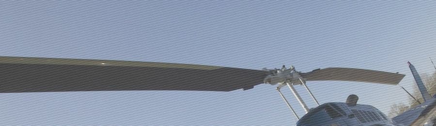 Close-up of a helicopter rotor against a blue sky.