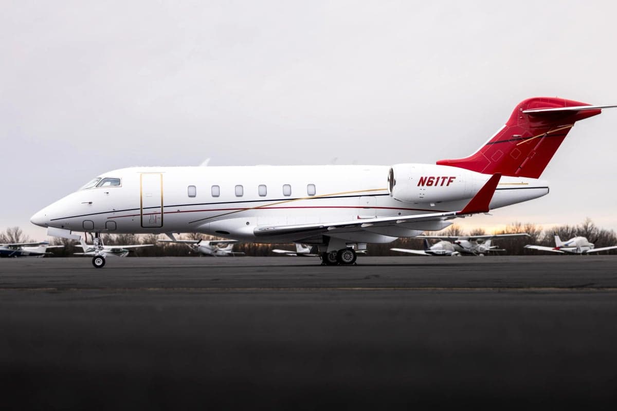 Side view of a Challenger 300 with red and gold accents on the tail and fuselage.