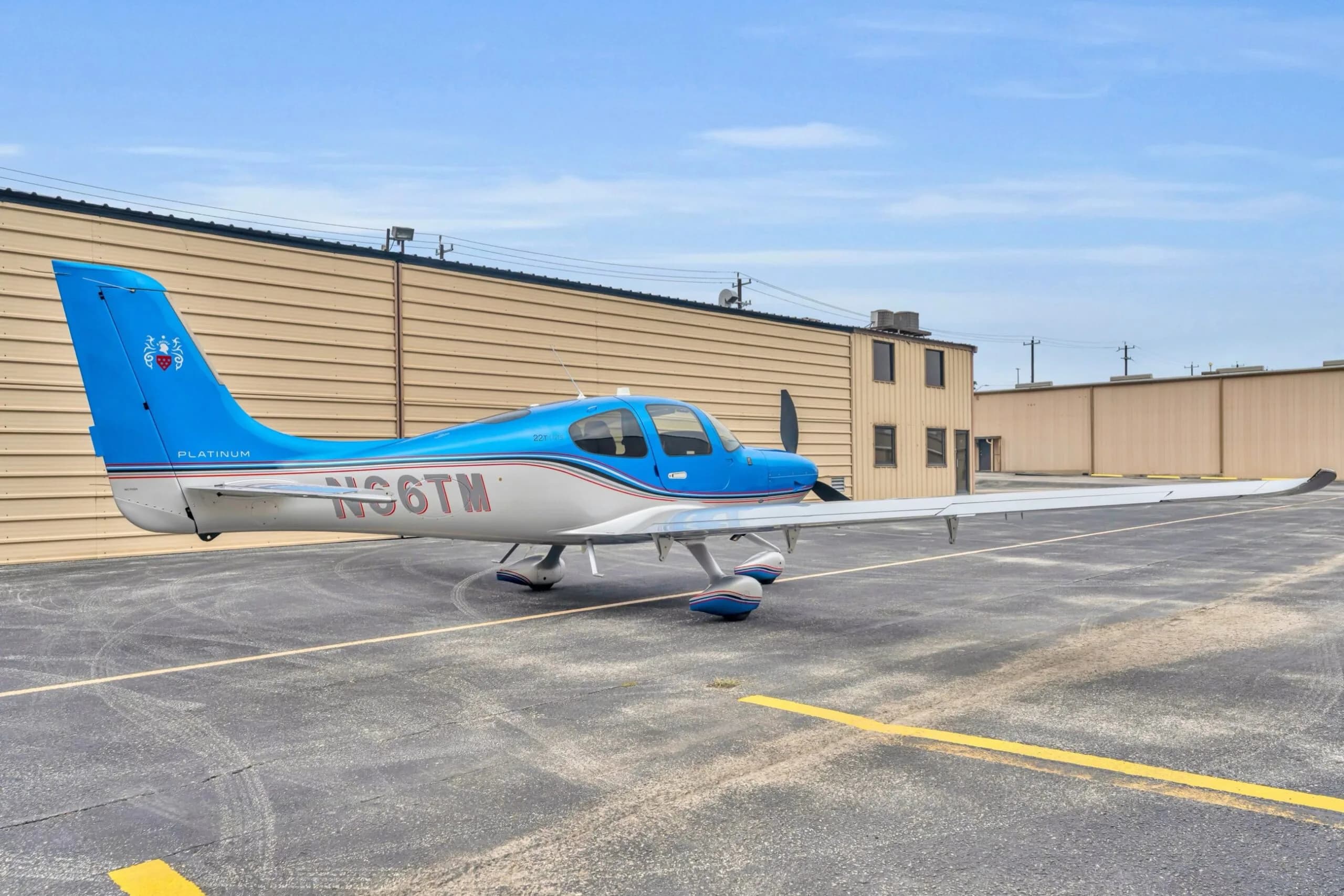 A three-quarter rear view of the blue and silver Cirrus SR22T GTS aircraft N66TM, parked on an asphalt ramp.