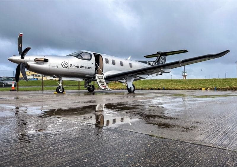 A Pilatus PC-12 aircraft with registration G-MDSZ parked on a wet tarmac.