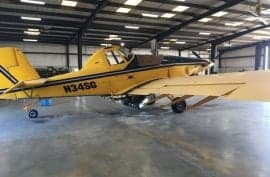 A yellow Air Tractor crop duster sits in a hangar.