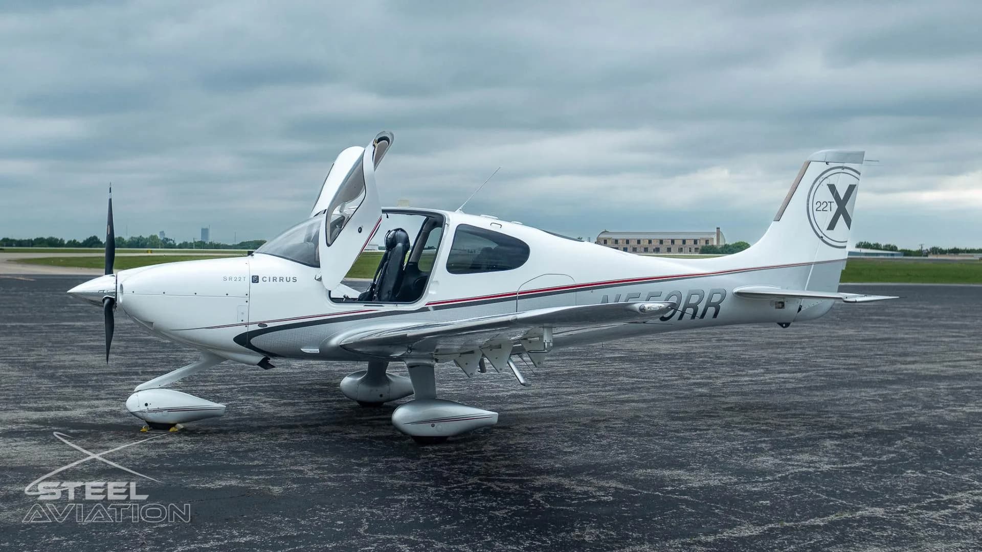 A white and silver Cirrus SR22T aircraft with registration N559RR has its gull-wing doors open on an airfield.