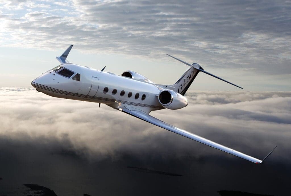 Gulfstream G450 in flight against a cloudy sky.