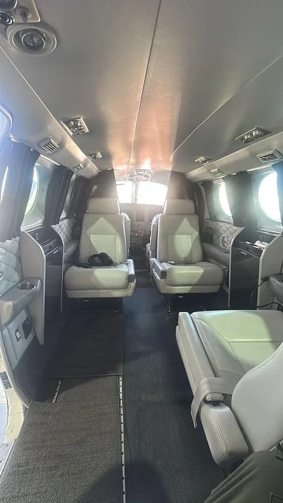 The interior cabin of a Cessna 421 aircraft, showing rows of light grey seats and a view towards the cockpit.