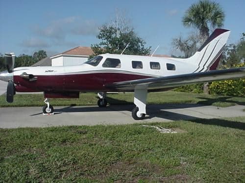 A Piper JetPROP aircraft is parked on the tarmac with a white and maroon paint scheme.