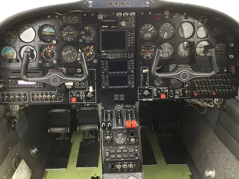 A detailed view of an aircraft cockpit with dual yokes, a full instrument panel, and center console controls.