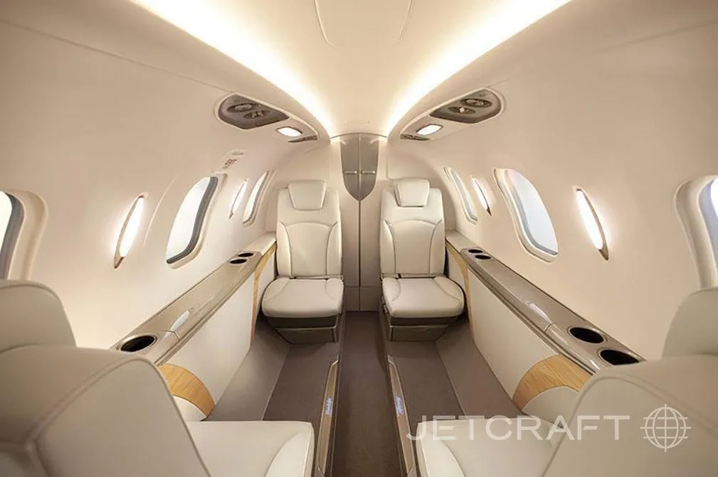 The interior cabin of a HondaJet shows two rows of beige leather seats and illuminated windows.