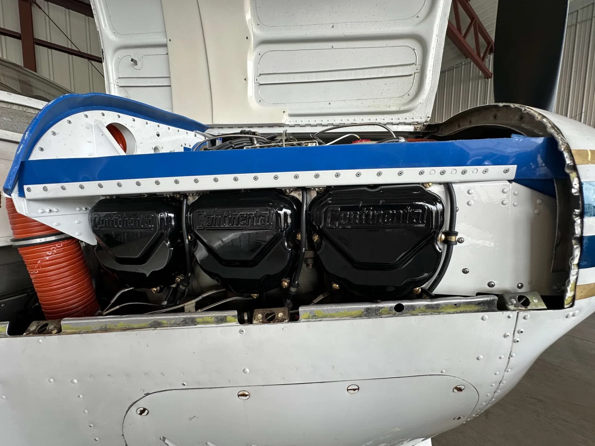 A close-up view of the Continental engine with black valve covers inside the open cowling of a Beechcraft Bonanza.