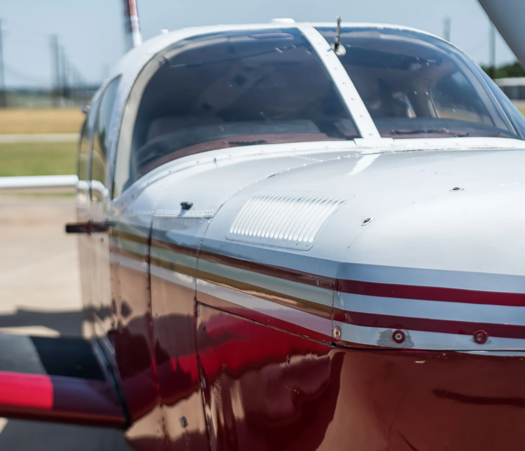 A close-up of the aircraft's cockpit windshield and white fuselage with red stripes.