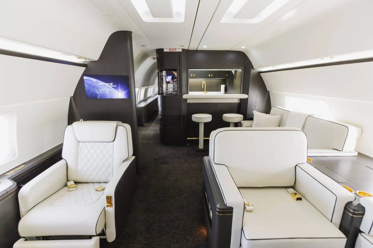 Interior view of the aircraft with white leather seating, a bar area, and a dark carpet.
