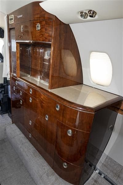 The aircraft's interior features a wooden cabinet with drawers and a countertop.