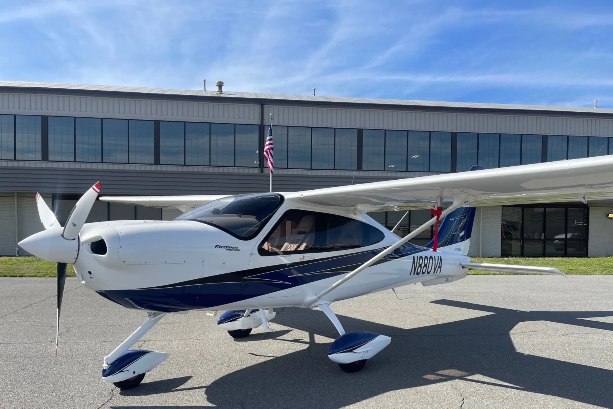 A white and blue light aircraft parked in front of a building.